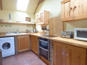 a kitchen with wooden cabinets and a sink and a microwave at Meadow Cottage in Fowey