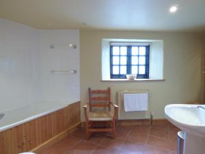 a bathroom with a tub and a chair and a sink at Meadow Cottage in Fowey +4 photos
