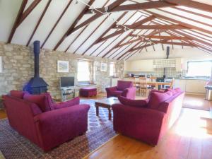 a living room with purple furniture and a stone wall at The Granary in Saint Erth