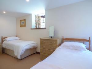 a bedroom with two beds and a dresser and a mirror at The Granary in Saint Erth