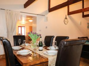 a dining room table with chairs and a bottle of wine at Kingfisher Barn in Liskeard