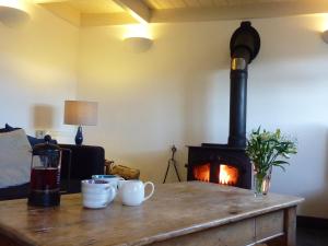 - une cheminée dans le salon avec une table et des tasses dans l'établissement Willow Cottage, à Lostwithiel
