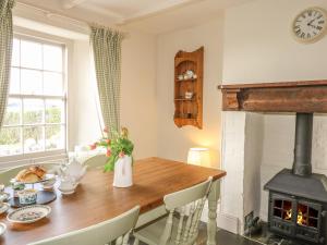 une cuisine avec une table en bois et une cheminée dans l'établissement Home Farm Cottage, à Boscastle