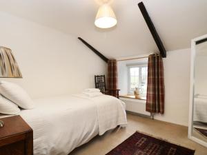 a bedroom with a white bed and a window at 13 Castle Hill in Lostwithiel