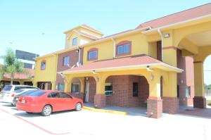 a red car parked in front of a yellow building at Raintree Inn and Suites in Houston