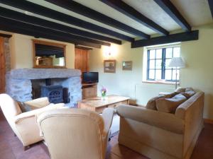 a living room with couches and a stone fireplace at Old Winery Cottage in Golant
