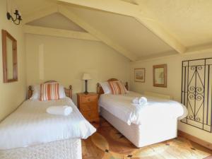 a bedroom with two beds and a wooden floor at Old Winery Cottage in Golant