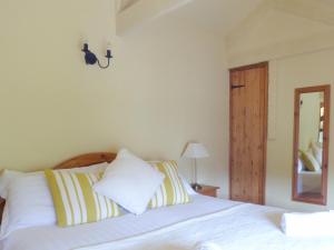 a bedroom with a bed with white sheets and a mirror at Old Winery Cottage in Golant +2 photos