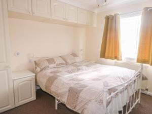 a white bed in a white bedroom with a window at 11 Pendarves in St Merryn