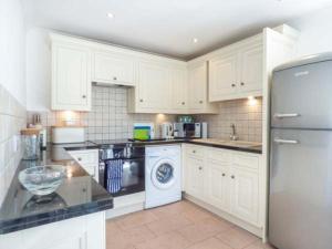 a kitchen with white cabinets and a washer and dryer at 7 Harlyn Cottages in St Merryn