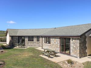 a stone house with two picnic tables in the yard at Seashells in Marazion