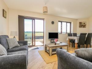 a living room with couches and a television and a table at Surfside in Marazion