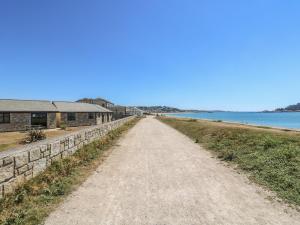 a dirt road next to a house and the water at Shoreline in Marazion