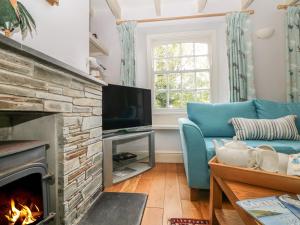 帕茲托的住宿－Trenouth Cottage，客厅设有壁炉和蓝色沙发。