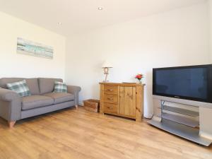 a living room with a couch and a flat screen tv at Ocean Heights in Porthtowan