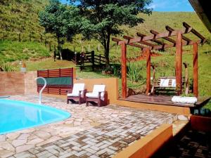 a patio with a swimming pool and a wooden pergola at Rancho Zé Valentim in São José dos Campos