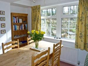 a dining room with a table with a vase of yellow flowers at Locks Cottage in Langcliffe