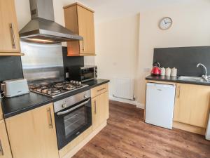 a kitchen with wooden cabinets and a stove top oven at No 1 Low Hall Cottages in Scalby +2 photos