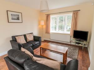 a living room with a leather couch and a tv at No 1 Low Hall Cottages in Scalby