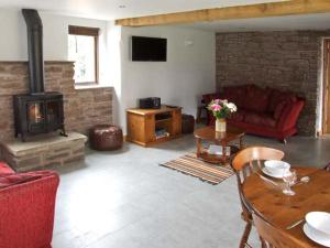 Bushmills في Bacton: غرفة معيشة مع موقد خشبي وأريكة