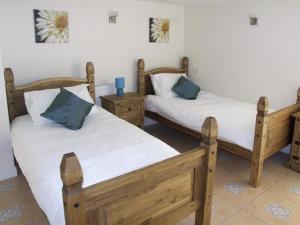 two wooden beds in a room with two tables at Rosewaters Cottage in Shrawley