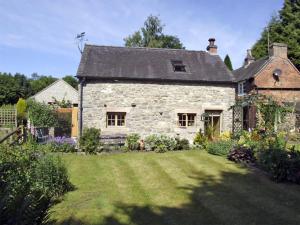 een oud stenen huis met een tuin in de tuin bij Church Barn in Tissington