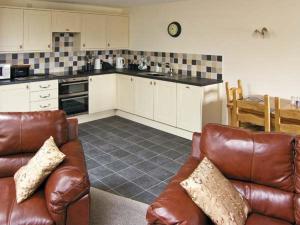 a living room with a couch and a kitchen at Ty Isaf Penrhyddion in Betws-y-coed