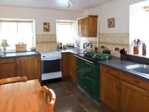una cocina con armarios de madera, mesa y fregadero en High Sprintgill Cottage en Ravenstonedale
