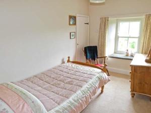 a bedroom with a bed and a desk and a window at High Sprintgill Cottage in Ravenstonedale +1 photo