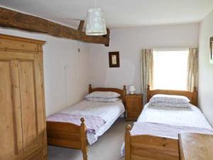 a bedroom with two beds and a window at High Sprintgill Cottage in Ravenstonedale