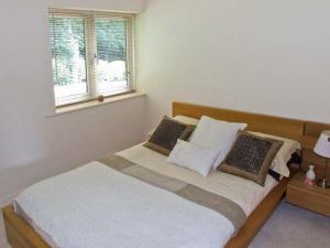 1 dormitorio con cama con almohadas y ventana en Clouds Hill, en Almondbury
