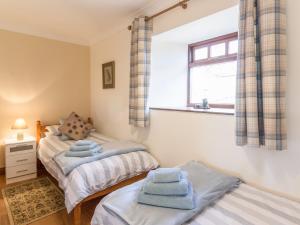 1 dormitorio con 2 camas individuales y ventana en Ridge Cottage en Longwitton