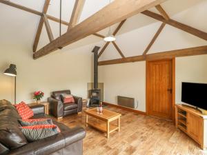 een woonkamer met lederen meubels en een flatscreen-tv bij Corner Barn in Winterborne Stickland