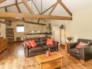 a living room with two leather couches and a table at Corner Barn in Winterborne Stickland