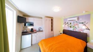 a small kitchen with an orange bed in a room at Orgona Apartman- és Nyaralóház in Balatongyörök