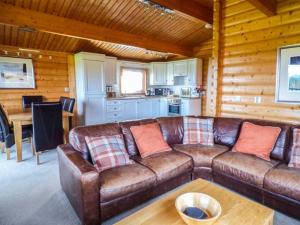 a living room with a brown leather couch and a table at Ty Pren in Porthgain