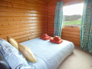 a bed in a log cabin with two towels on it at Ty Pren in Porthgain