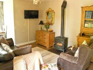 uma sala de estar com um sofá e um fogão a lenha em Carreg Rhys em Llangristiolus