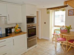 een keuken met witte kasten, een tafel en een fornuis bij Piggery Cottage in Wigton