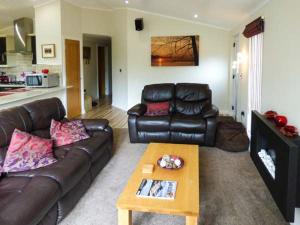 uma sala de estar com um sofá de couro e uma mesa de centro em High View Lodge em Windermere