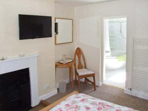 a bedroom with a fireplace and a chair and a television at 73 Ravensdale Cottages in Millers Dale