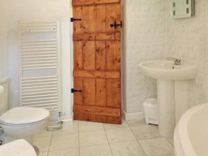 ein Badezimmer mit einer Holztür, einem WC und einem Waschbecken in der Unterkunft 73 Ravensdale Cottages in Millers Dale