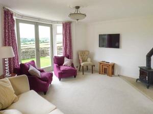 a living room with purple furniture and a tv at Cringles House in Silsden