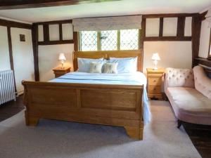 a bedroom with a large wooden bed and a couch at Tudor Wing in Chiddingstone