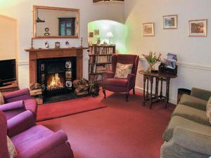 a living room with a fireplace and purple chairs at Aqueduct Cottage in Chirk