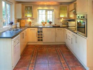 a large kitchen with white cabinets and a tile floor at Aqueduct Cottage in Chirk