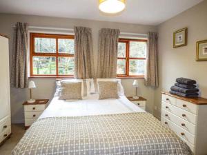 a bedroom with a large bed and two windows at 4 Adwy'r Nant in Beddgelert