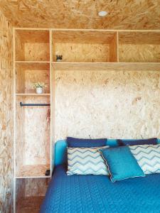 a bed with blue pillows in a small room at Refúgio do Valouto in Torneiro