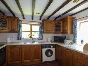 a kitchen with wooden cabinets and a washing machine at Chevinside Cottage in Hazelwood