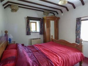 a bedroom with a large bed with a red blanket at Chevinside Cottage in Hazelwood